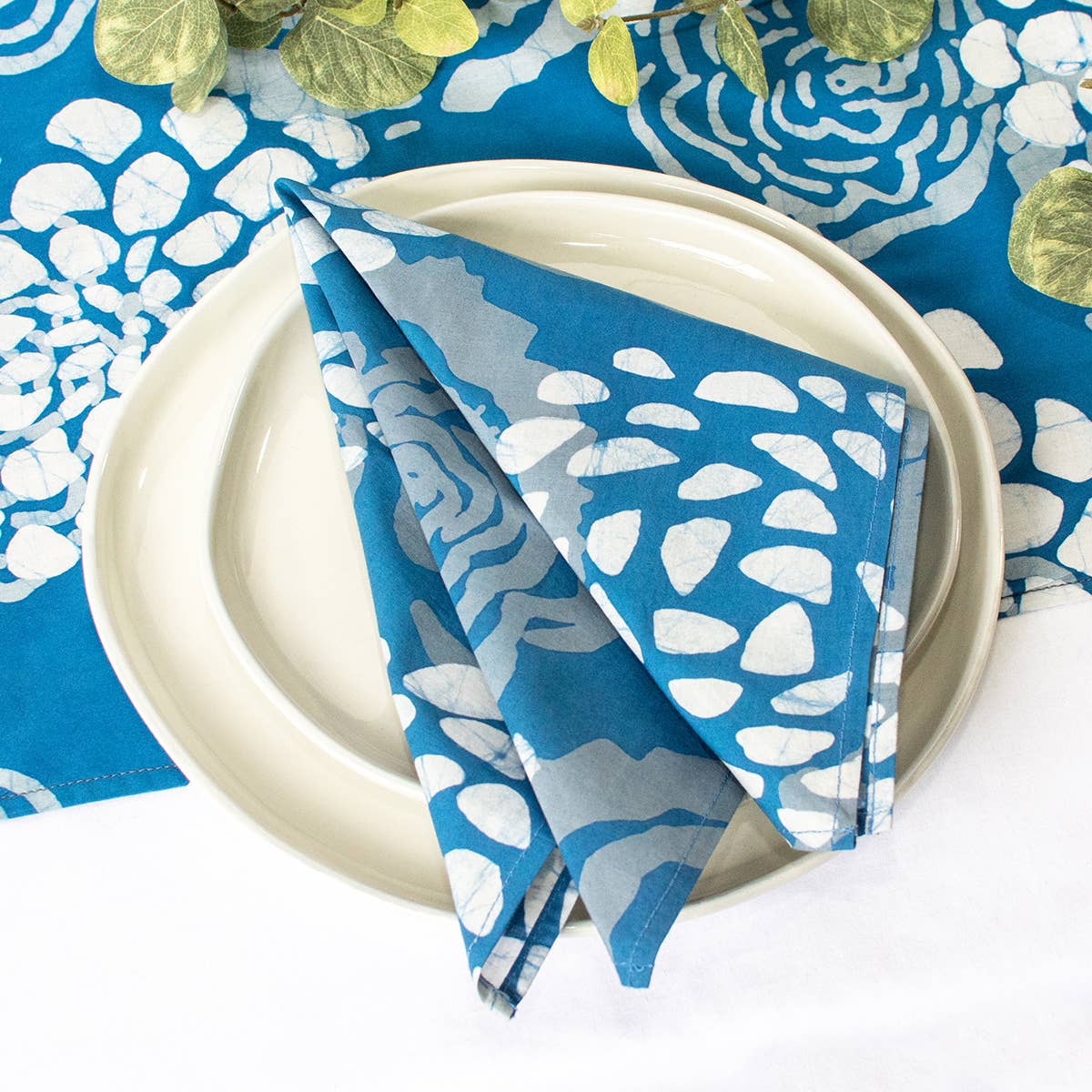 Organic Batik Napkins by Global Mamas with indigo floral batik patterns on soft fabric, ideal for table setting and home decor.