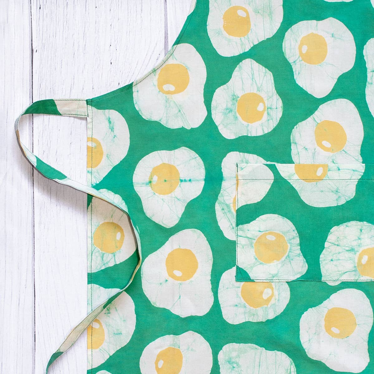 Reversible organic batik apron from Global Mamas featuring vibrant patterns in orange and yellow with tie straps.
