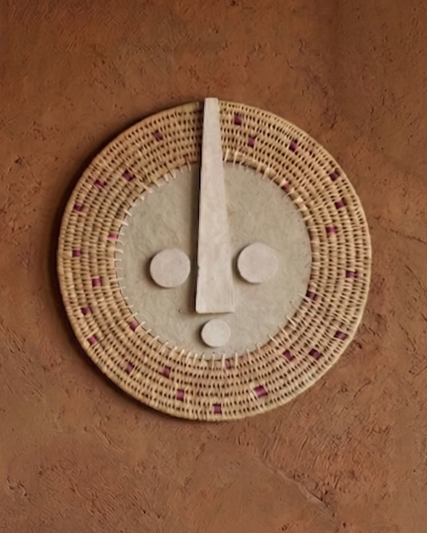 Ceramic wall art with face design on a textured brown wall